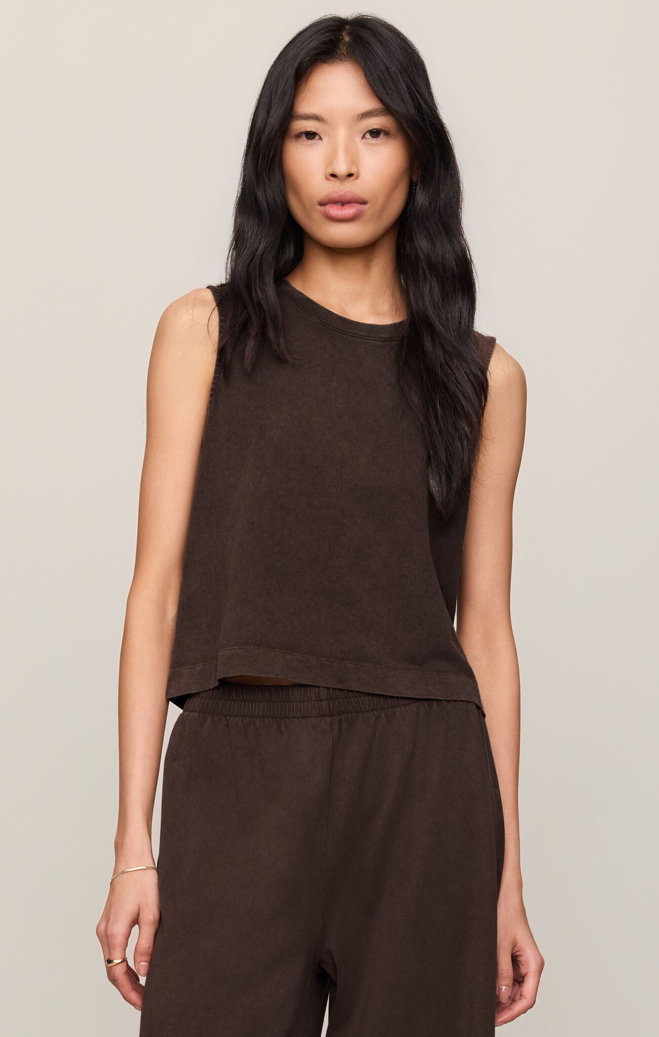 Woman wearing a dark chocolate brown Sloane sleeveless top and pants against a neutral background