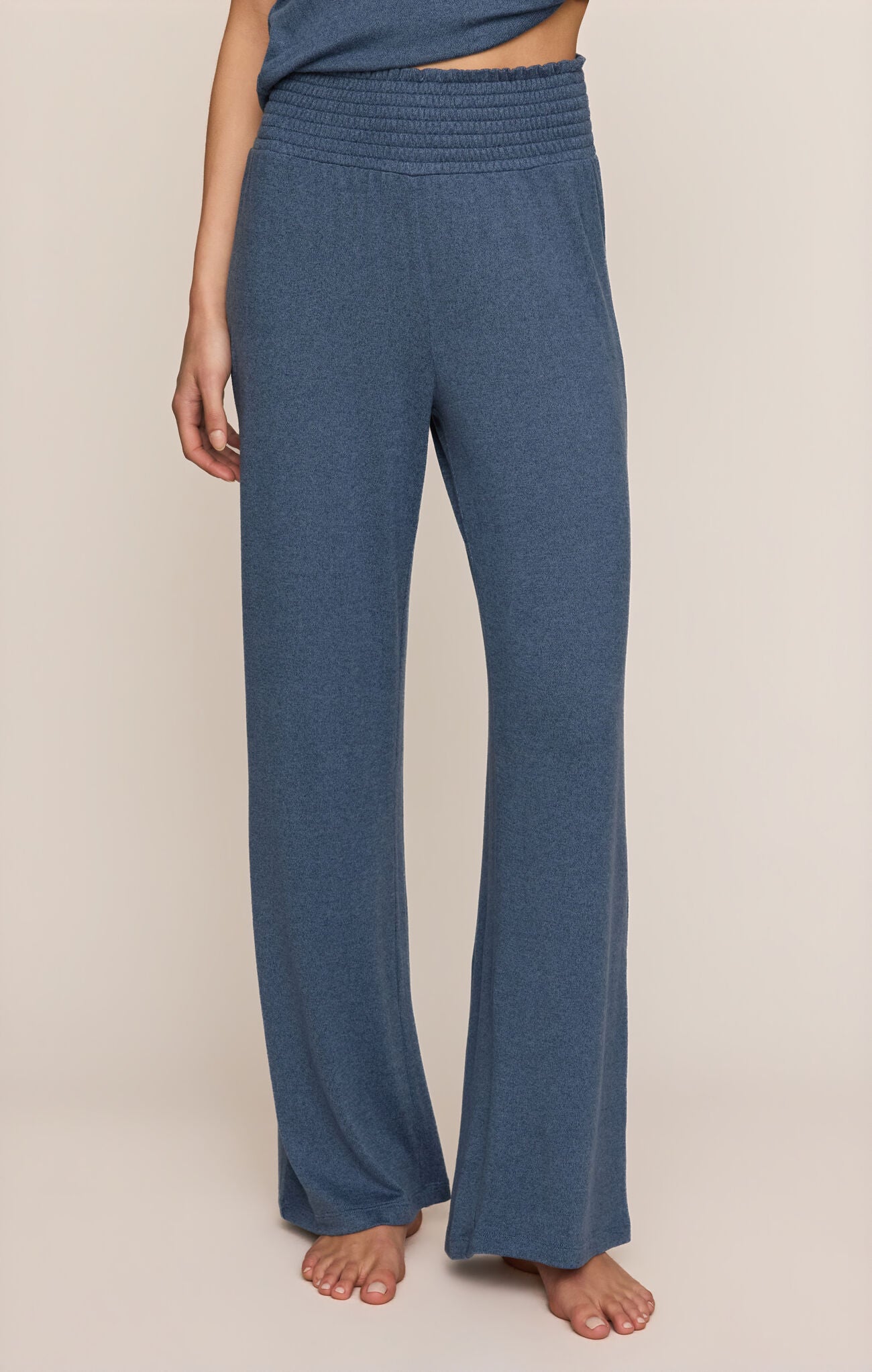 Front view of person wearing Dawn Smocked pants in True Navy color on a beige background