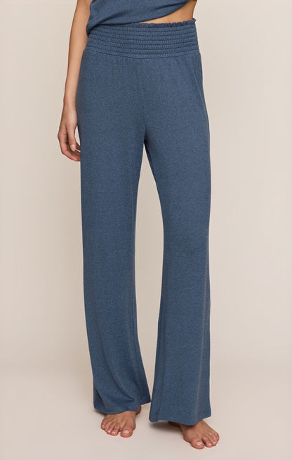 Front view of person wearing Dawn Smocked pants in True Navy color on a beige background