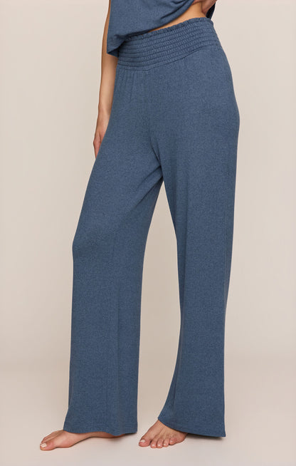 Side view of true Navy Smocked pants worn by a person on a beige background