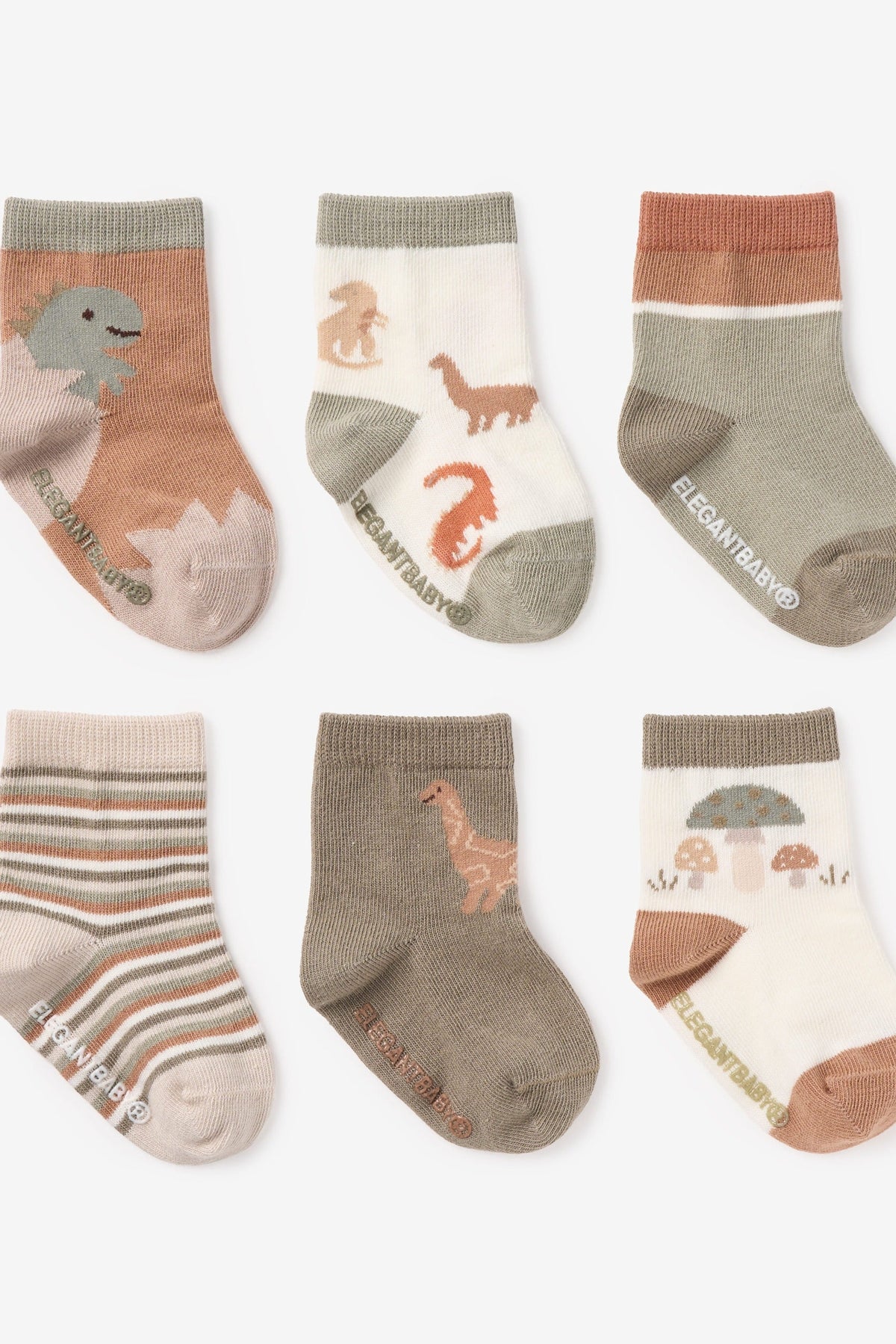 Six pairs of children's ankle socks arranged in two rows on a light gray background. The socks feature various earthy tones including terracotta, sage green, taupe, and cream, with some pairs decorated with dinosaur and mushroom illustrations and one pair featuring horizontal stripes.