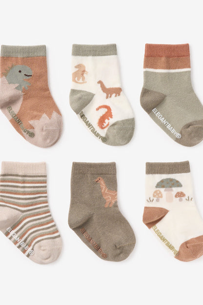 Six pairs of children's ankle socks arranged in two rows on a light gray background. The socks feature various earthy tones including terracotta, sage green, taupe, and cream, with some pairs decorated with dinosaur and mushroom illustrations and one pair featuring horizontal stripes.