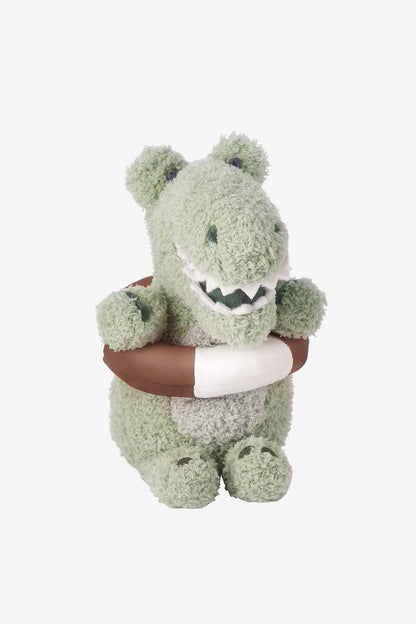 A plush crocodile toy in a textured sage green fabric, holding a brown and white life preserver, set against a plain light gray background.