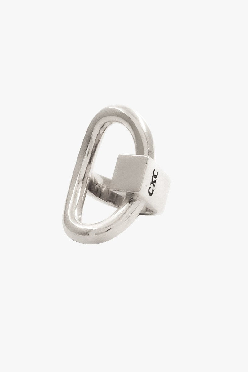 A polished silver 'Queen' ring with a unique open, looped oval design and a small square inset, featuring the brand name 'CXC' engraved on the band, set against a plain light gray background.