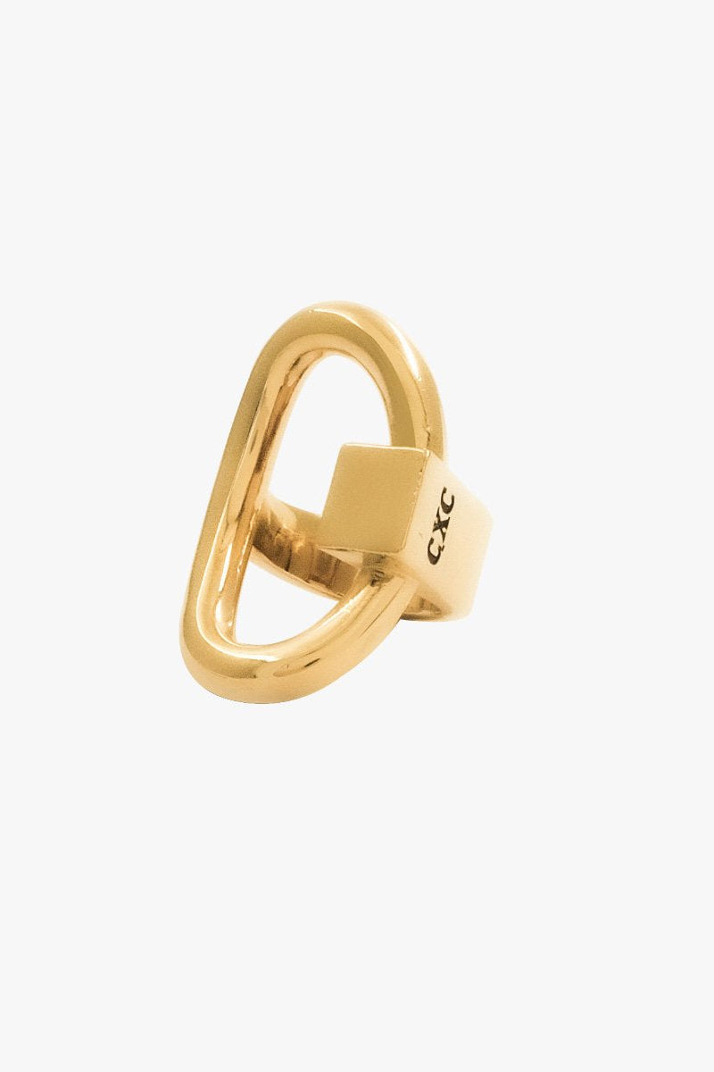 A gold 'Queen' ring with a unique elongated oval design and a square block detail on the side, featuring the engraved brand name 'CXC'.