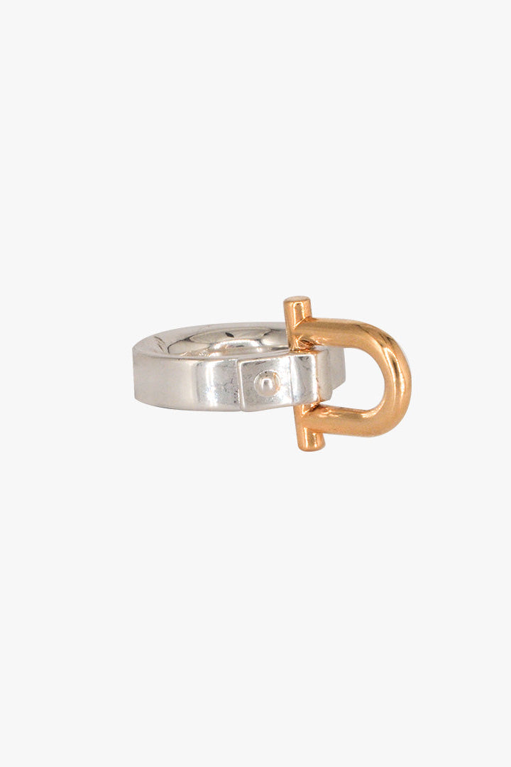 A minimalist Shackle ring featuring a polished silver band with a prominent rose gold D-ring closure, shown against a solid off-white background.