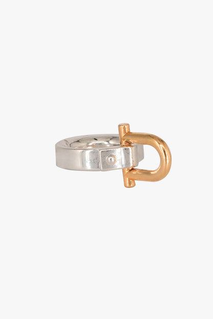 A minimalist Shackle ring featuring a polished silver band with a prominent rose gold D-ring closure, shown against a solid off-white background.