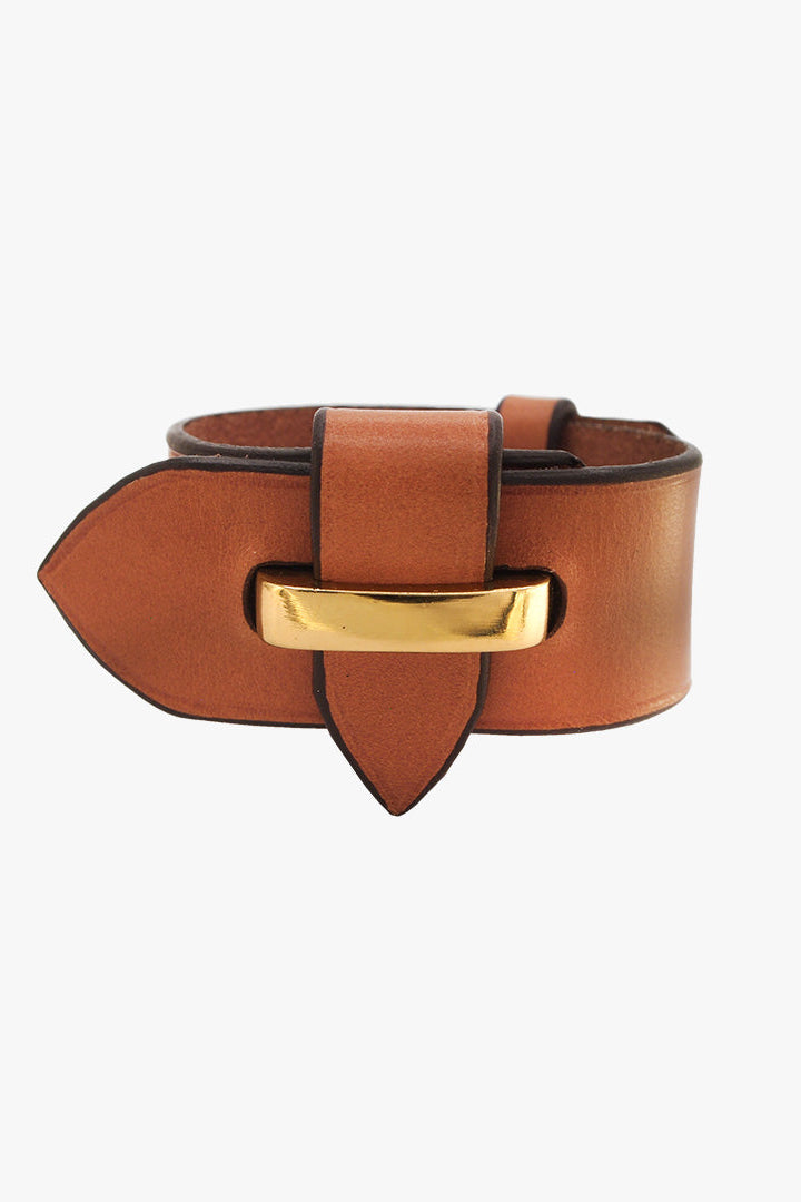 A wide brown leather belt looking 'Weather Vane' bracelet with a distinctive pointed tip and a polished gold-tone metal buckle, shown on a light gray background.