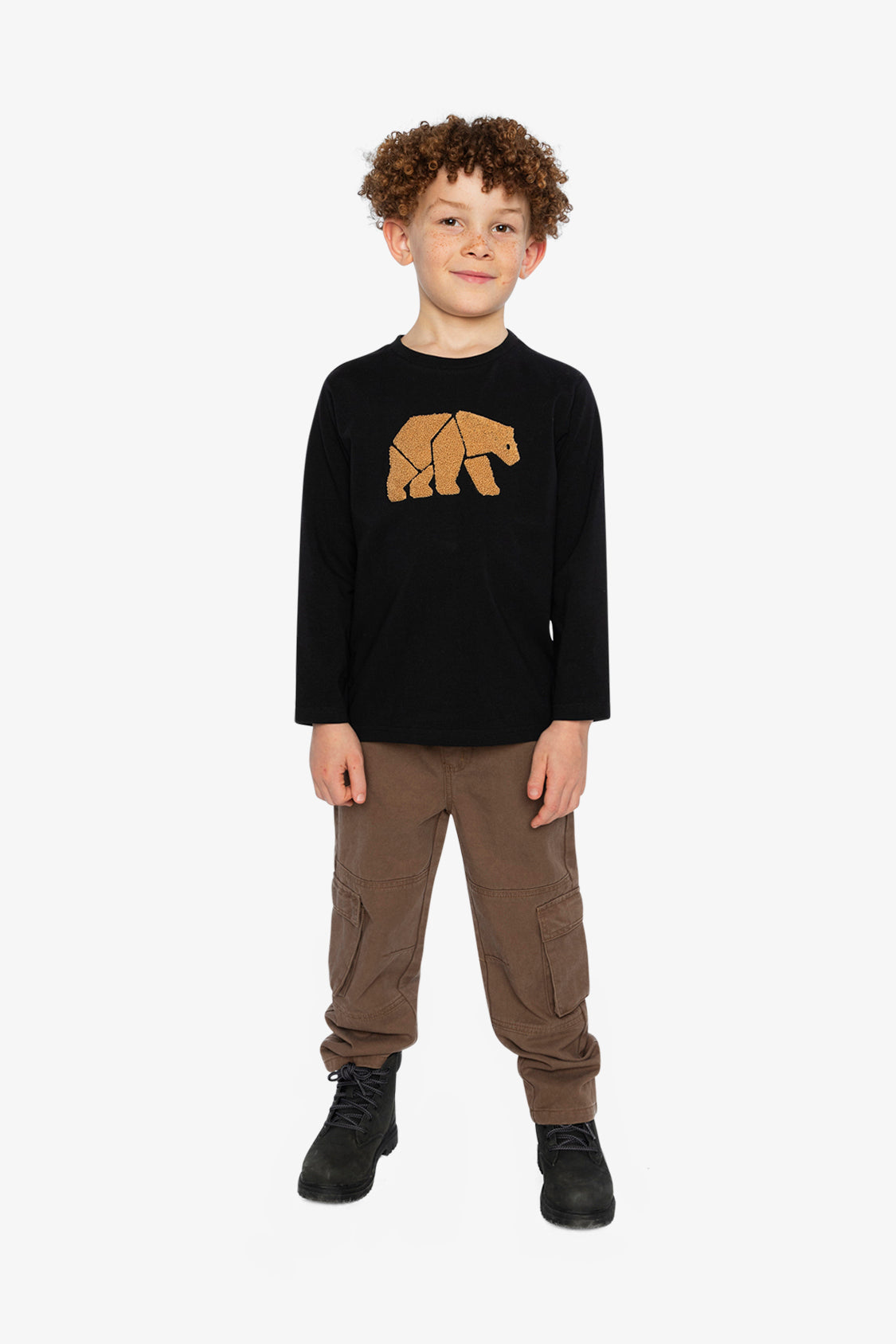 Child wearing a black long-sleeve shirt with a bear graphic and brown pants on a white background
