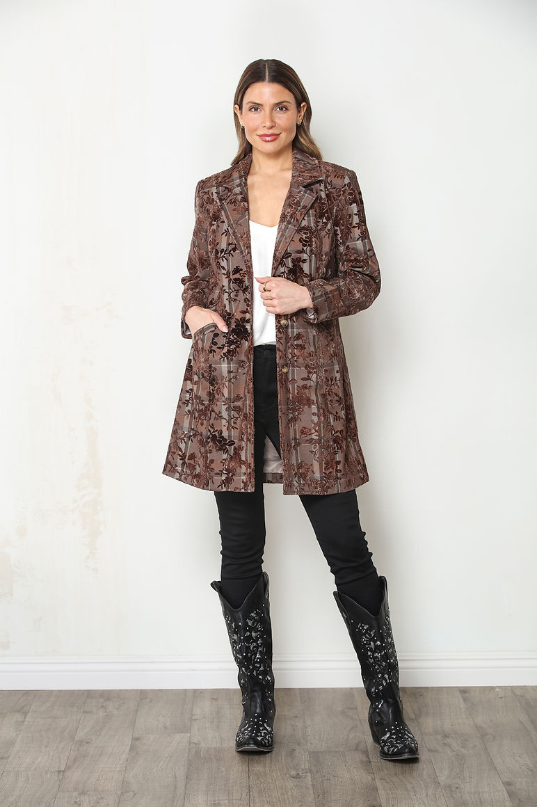 A woman modeling an espresso brown and beige flocked plaid floral patterned open-front mid-length jacket over a white top and black pants with black cowboy boots.