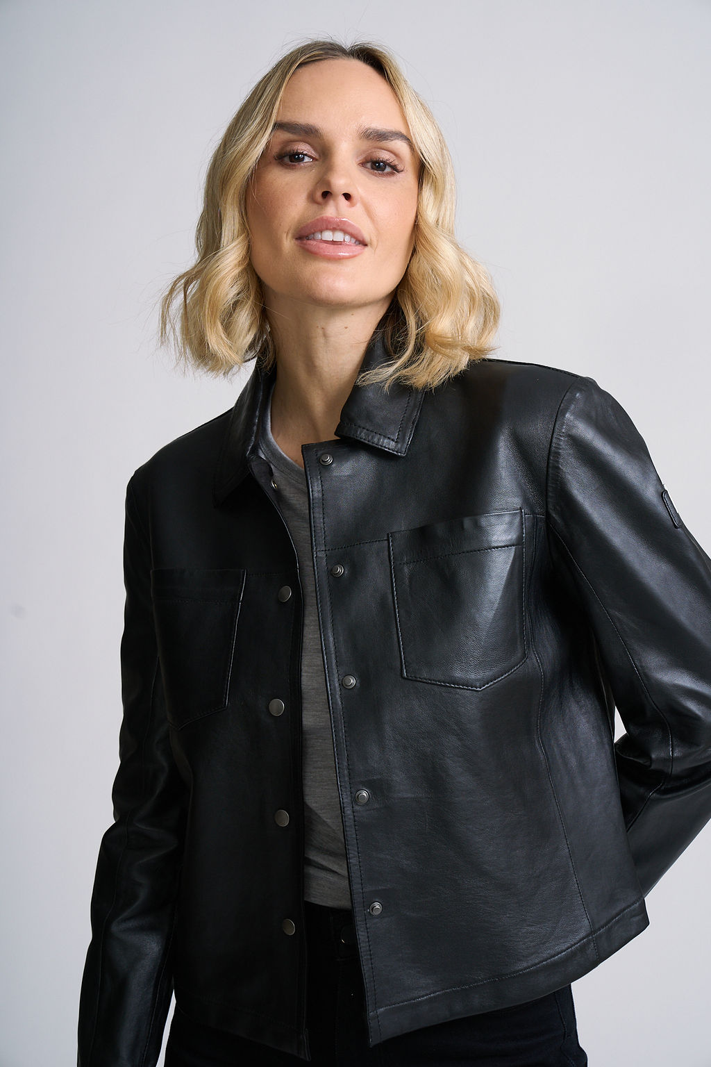 Woman wearing a black leather jacket against a plain background