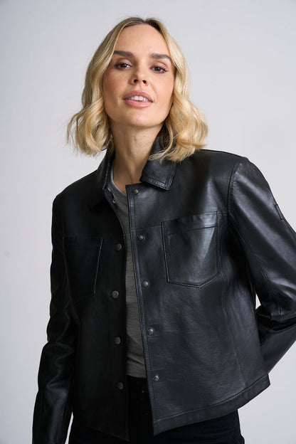 Woman wearing a black leather jacket against a plain background