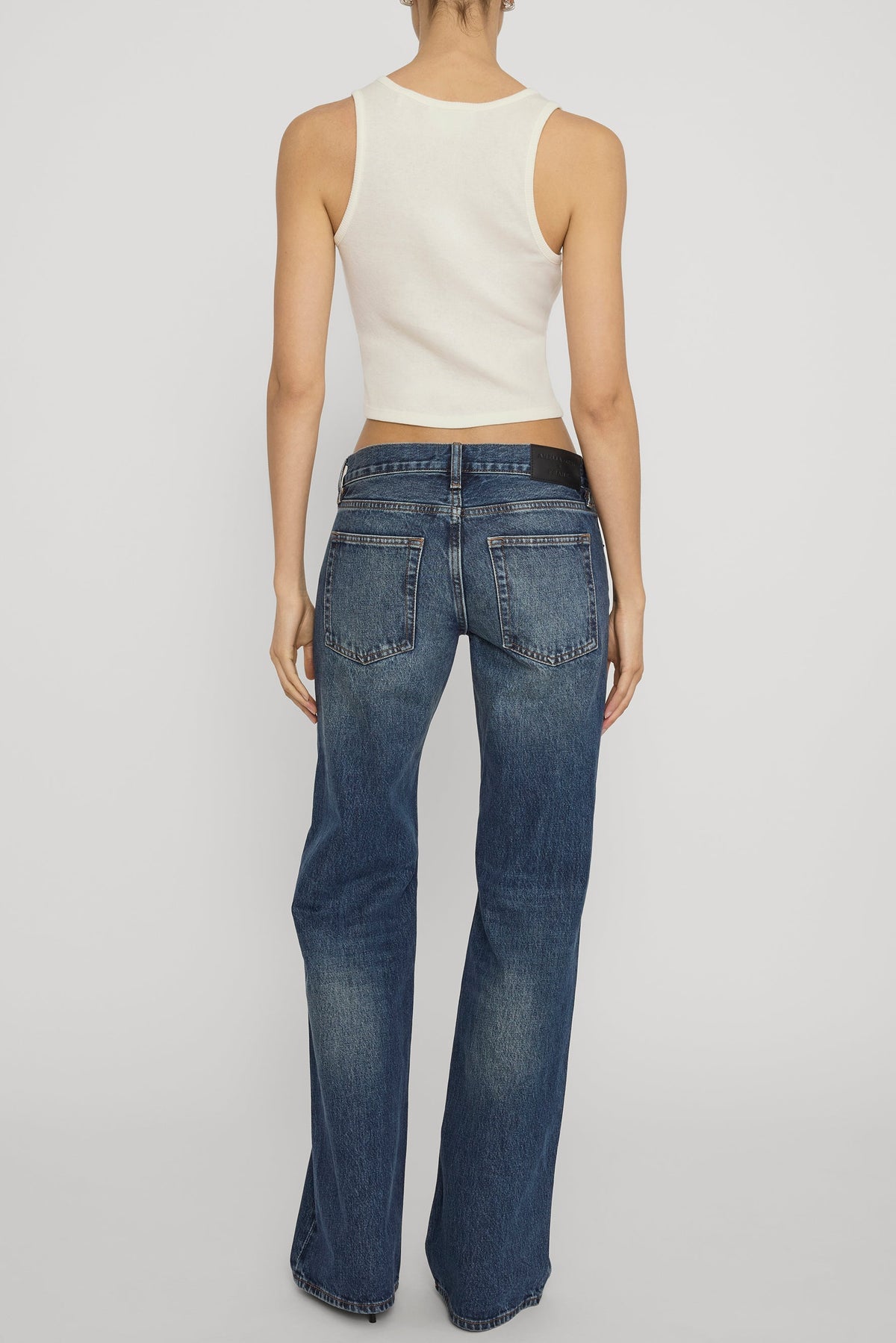 Back view of woman wearing a white tank and The Gray jeans in Tolerate wash 