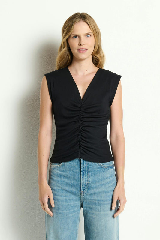 Woman wearing a black sleeveless Lune shirred front tank top and blue jeans against a white background
