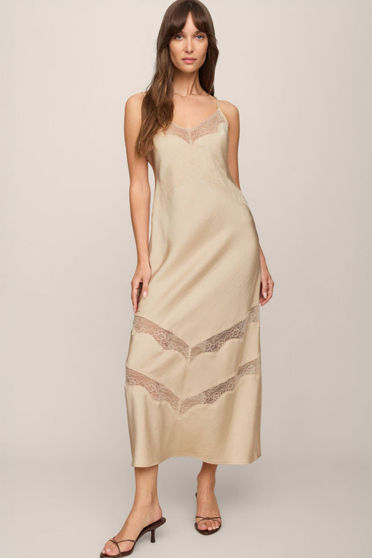 Woman wearing a chalk beige slip dress with lace details on a plain background