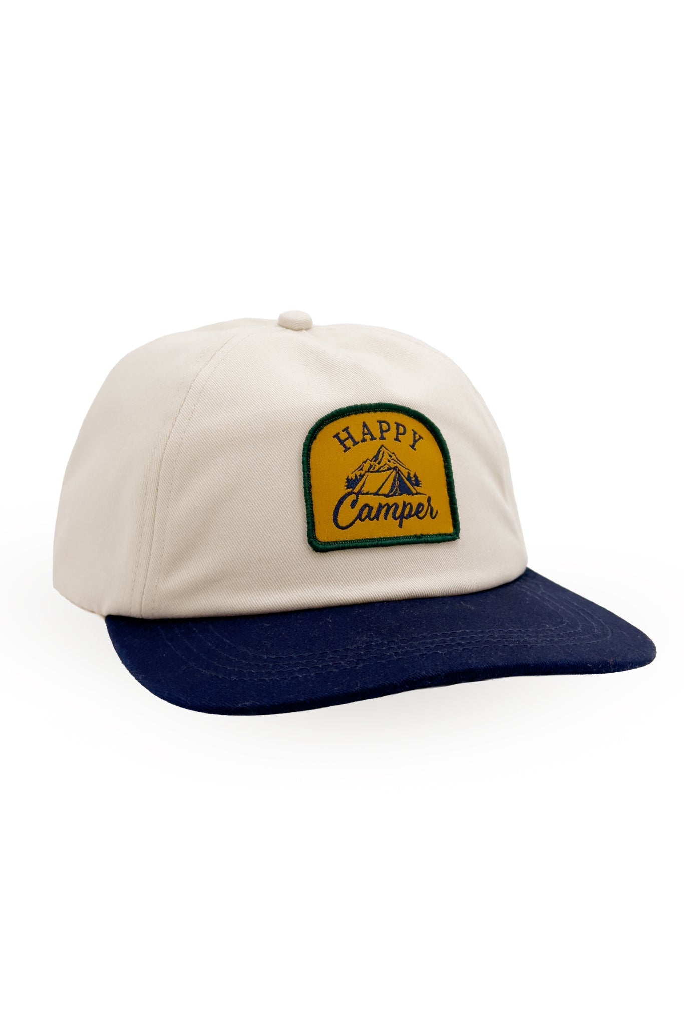 A snapback style baseball cap with an off-white crown and a navy blue curved brim, featuring a yellow and green embroidered patch on the front that reads 'Happy Camper'.