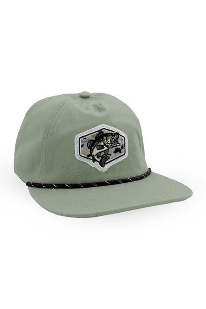 A sage green flat-brim cap featuring a black and white embroidered patch of a fish inside a shield on the front, with a black rope detail wrapped around the base of the crown, set against a plain white background.