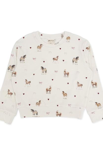 An off-white long-sleeve crewneck sweatshirt featuring an all-over print of horses, pink bows and small pink hearts, laid flat against a white background.