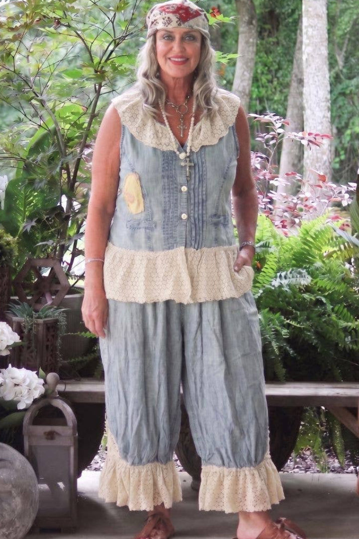 Woman wearing the Vintage whispers bloomers in chambray with cream lace detailing at the bottom and a matching top against a garden background 