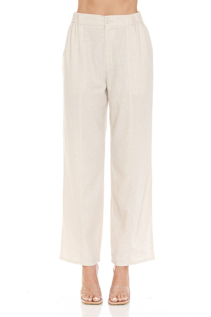 A model is wearing a pair of high-waisted, wide-leg cropped pants in a light cream or khaki linen-like fabric, paired with clear high-heeled sandals against a solid white background.