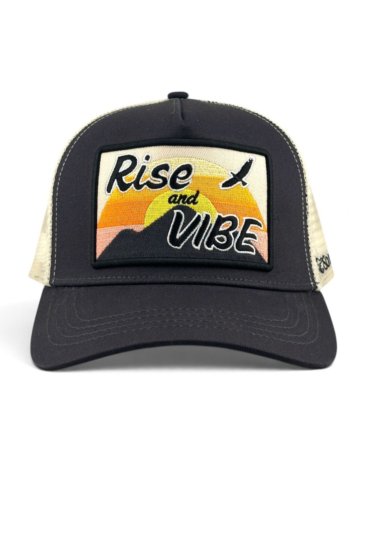 A black trucker hat with beige mesh side panels and a rectangular front patch featuring a sunset graphic and the words 'Rise and VIBE'.