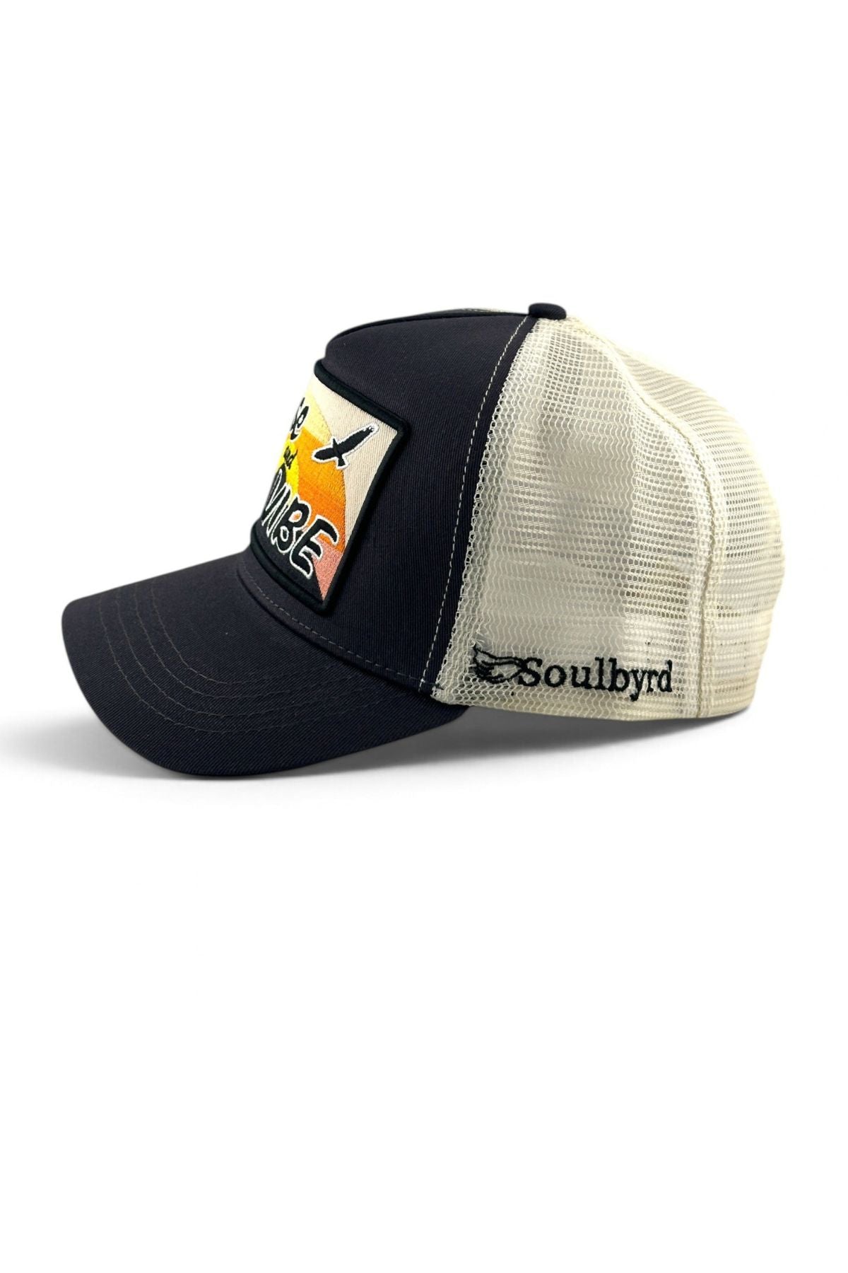 A black and cream trucker hat with a mesh back, featuring a 'Paradise' patch on the front and the 'Soulbyrd' brand name embroidered on the side.