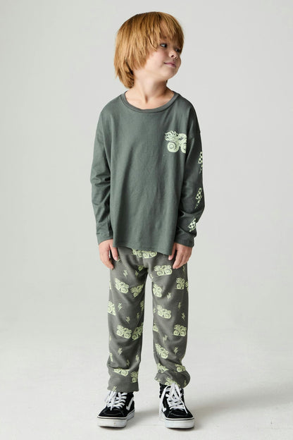 Boy wearing a safari green long sleeve tee with a monster truck graphic print on the front and down one arm paired with matching safari green monster truck pants