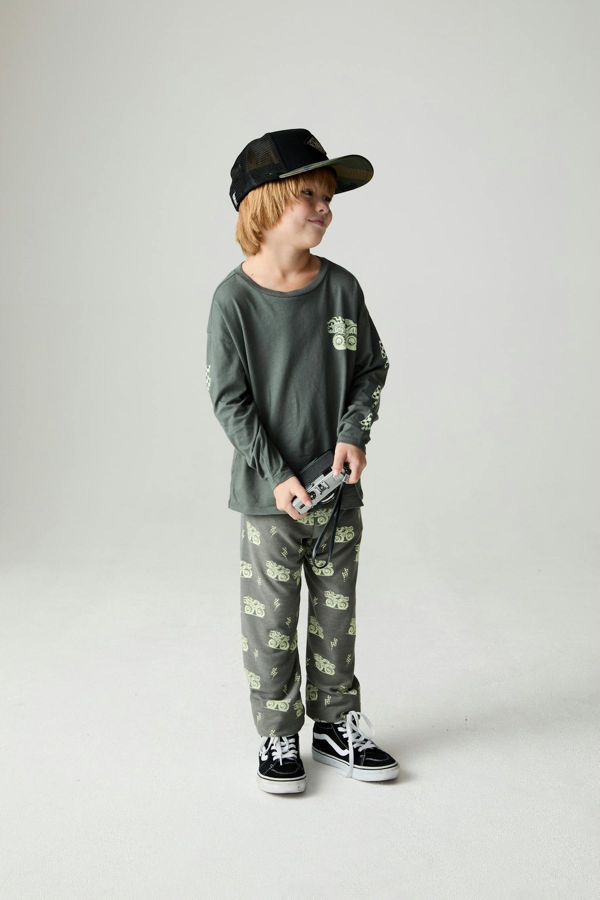 Child wearing a safari green long sleeve monster truck tee with matching safari green monster truck jogger style pants 