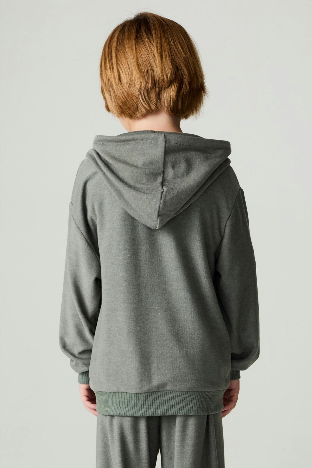 A boy shown from the back wearing a safari green hoodie and matching pants 