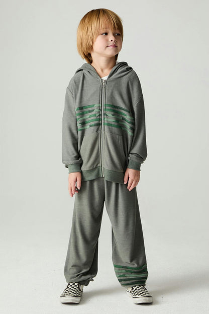 A boy wearing a safari green matching hoodie and pant set with camo details 