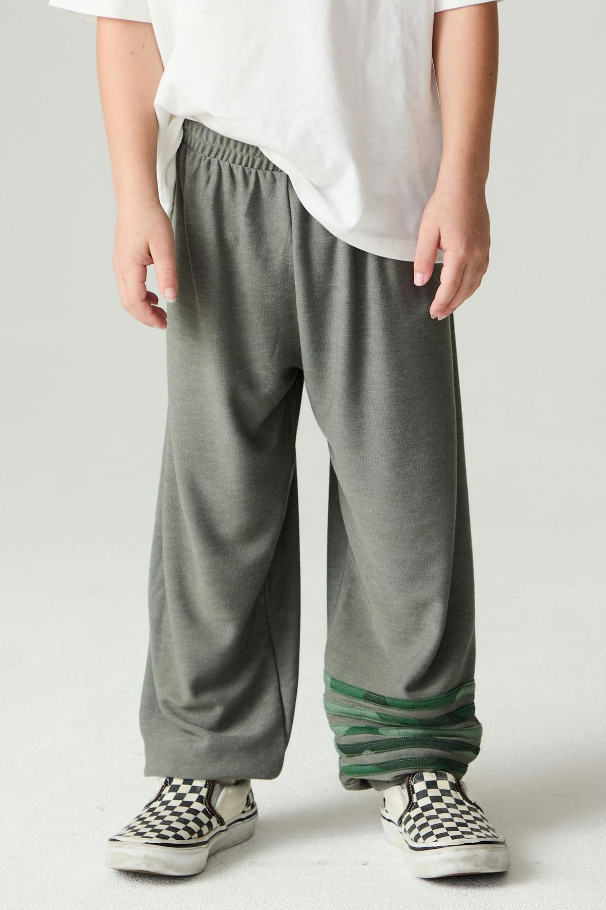 Person wearing safari green jogger style pants with green camo stripe accents on a plain background
