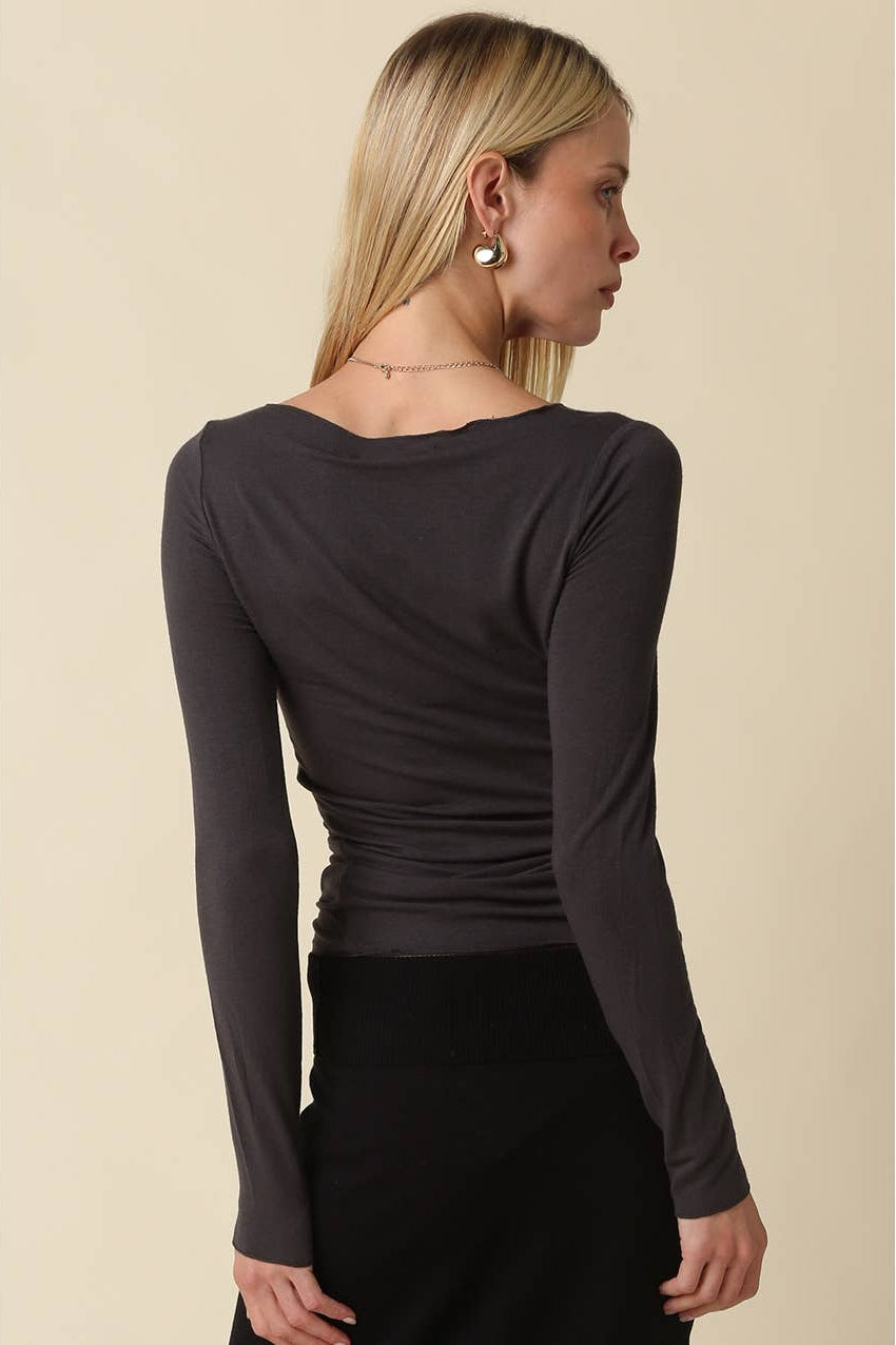 Woman shown from the back wearing a long sleeve dark charcoal shirt with black pants