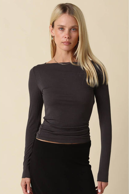 Woman wearing a dark charcoal long sleeve shirt with black pants 