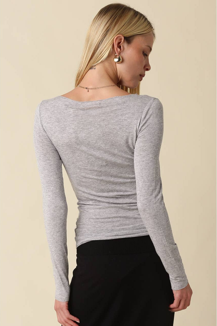 Woman shown from the back wearing a light heather grey long sleeve shirt with black pants 