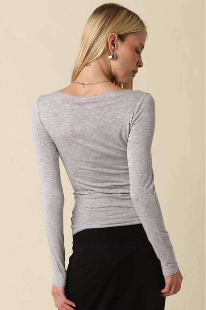 Woman shown from the back wearing a light heather grey long sleeve shirt with black pants 