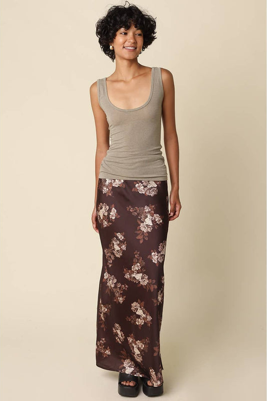 Woman wearing a light brown tank top with a brown and cream floral maxi skirt