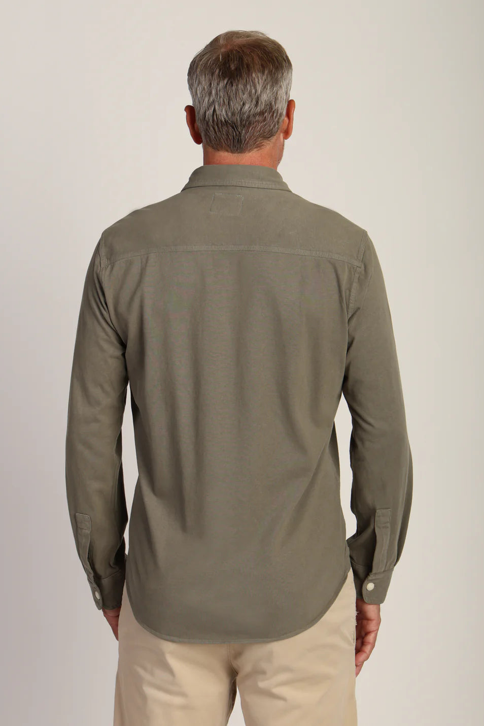 Back view an wearing long sleeve button down shirt in agave color 