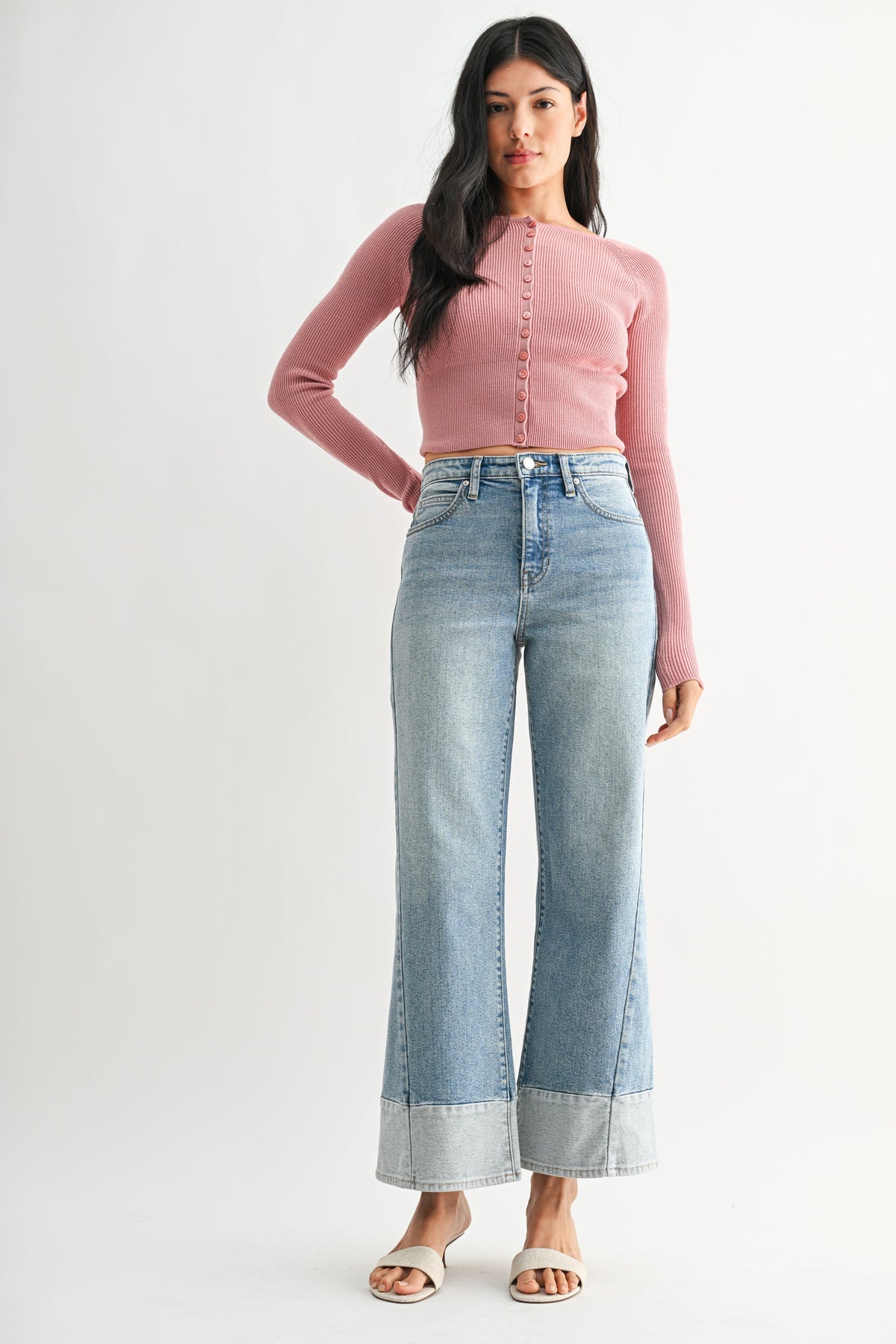 Woman wearing a pink long-sleeve top and light denim two toned wide-leg blue jeans on a white background
