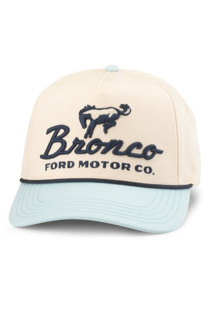 A structured baseball cap featuring a cream-colored crown with dark navy blue embroidered 'Bronco Ford Motor Co.' text and horse logo, paired with a light blue visor.
