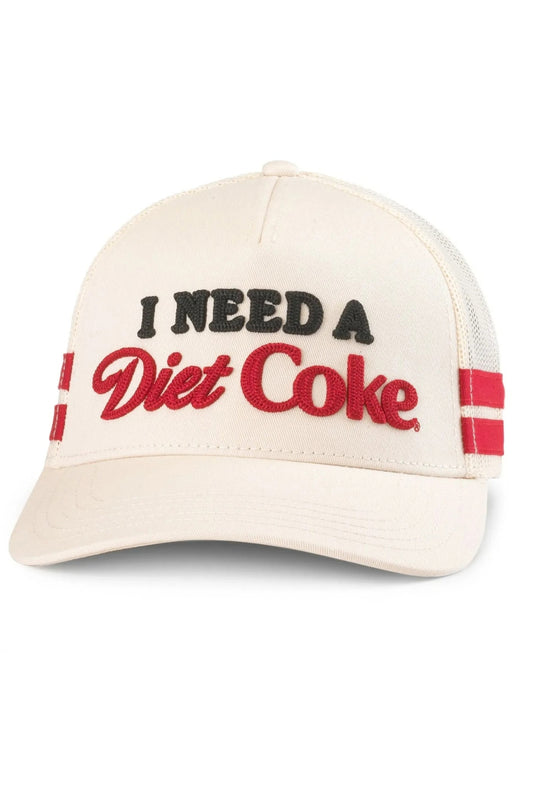 An off-white trucker hat with 'I NEED A Diet Coke' embroidered on the front. The text 'I NEED A' is in black, 'Diet Coke' is in red script, and there are red and black stripes on the side mesh panels.