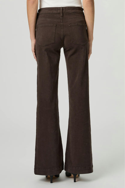 A person shown from the back wearing Leenah rich chocolate brown wide-leg flare jeans, paired with a white top and black heels, against a light gray studio background.