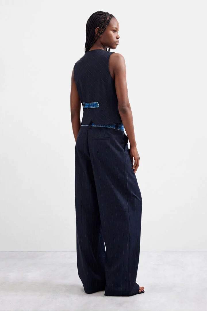 A model shown from the back wearing a dark navy sleeveless top and matching navy long wide-leg woven trousers, standing against a plain white studio background.