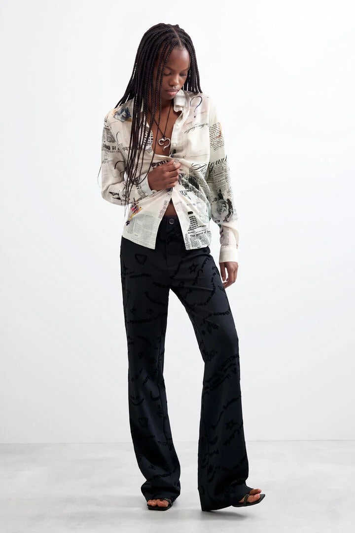 Woman wearing Black Long Printed Trousers and a white patterned shirt 