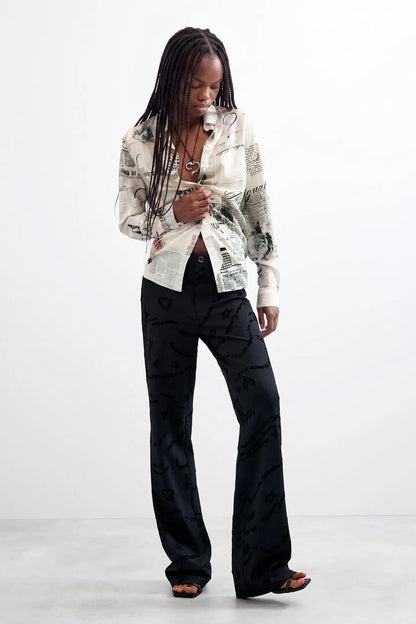 Woman wearing Black Long Printed Trousers and a white patterned shirt 