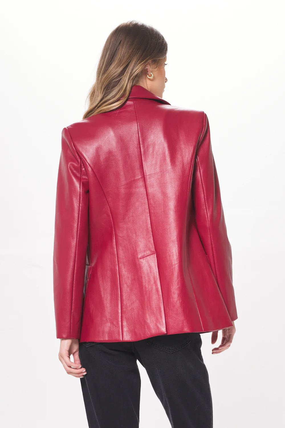 Woman shown from the back wearing a ruby faux leather blazer and black pants.