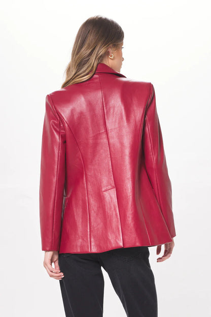 Woman shown from the back wearing a ruby faux leather blazer and black pants.