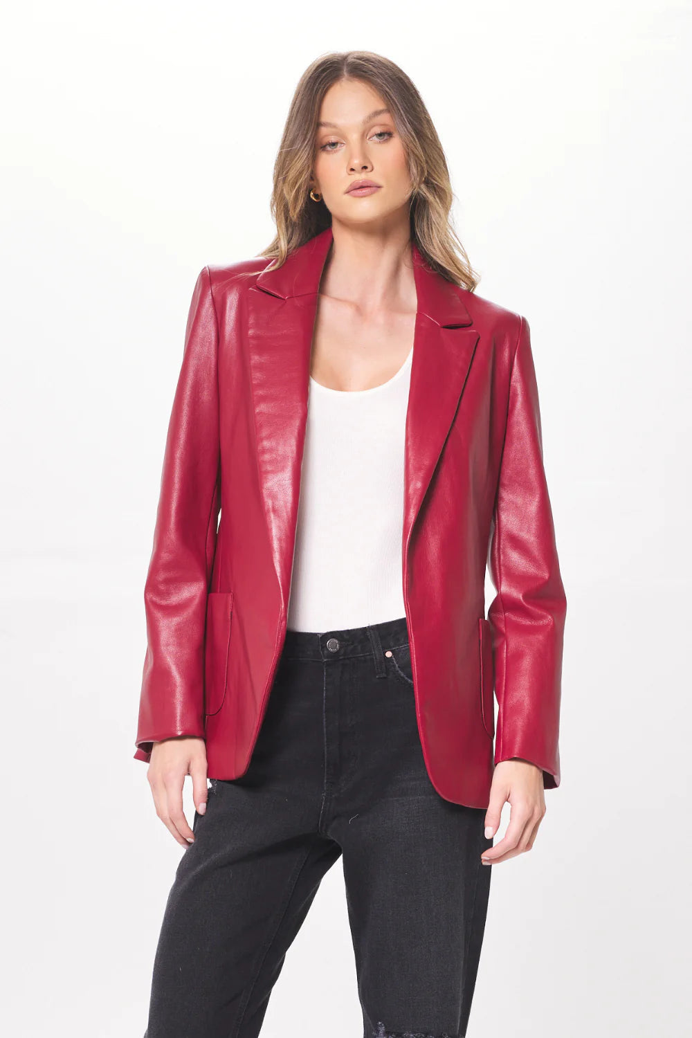 Woman wearing a ruby faux leather blazer with a white undershirt and black pants. 