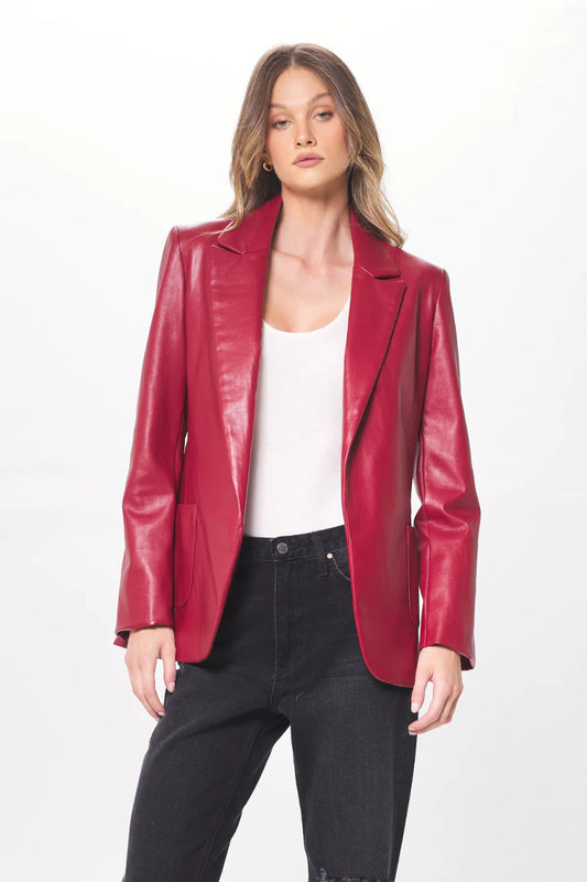 Woman wearing a ruby faux leather blazer with a white undershirt and black pants. 