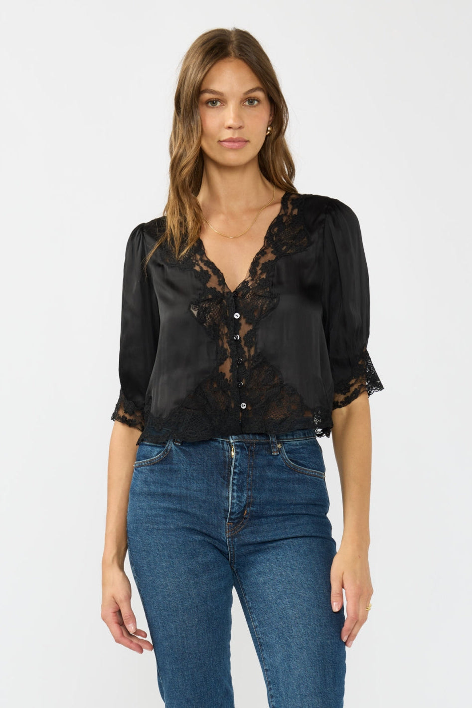 Woman wearing a black lace blouse and blue jeans on a white background