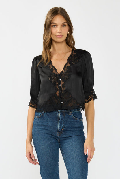 Woman wearing a black lace blouse and blue jeans on a white background